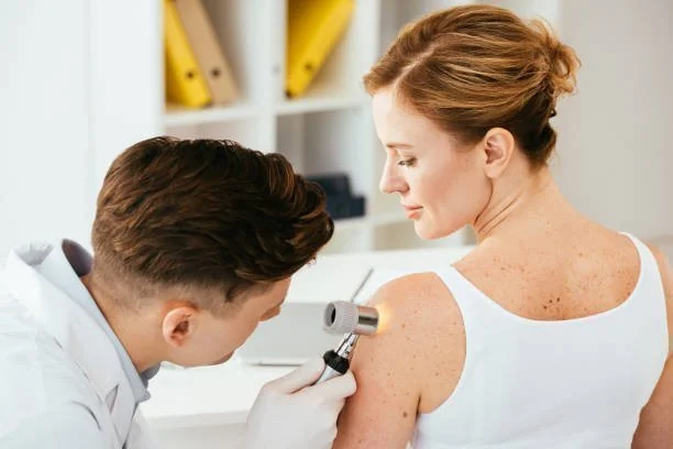 Médico examinando pintas na pele de paciente com dermatoscópio
